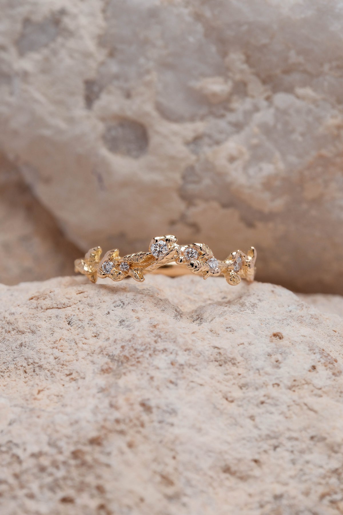 Close-up on natural stone background of handmade 18K yellow gold Mûres Sauvages ring, set with natural white diamonds, It draws its inspiration from brambles and untamed nature, crafted in Lyon, France
